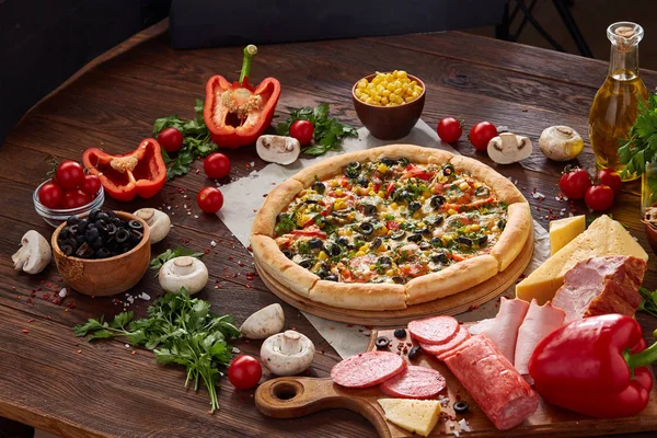 Pizza natürmort. Fırından yeni çıkmış pizza ve ahşap zemin üzerine düzenlenmiş bileşenleri.