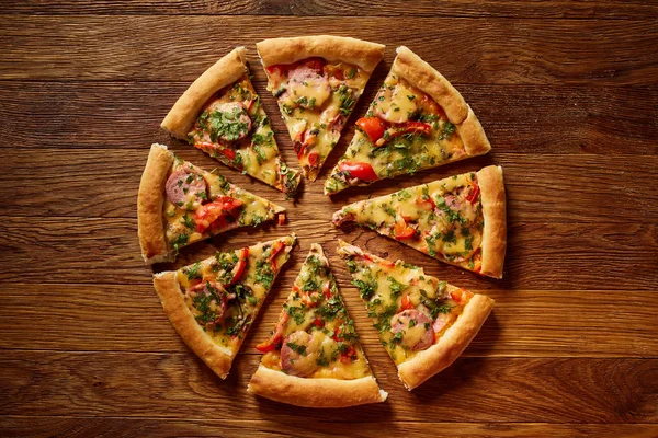 Freshly baked pizza divided into slices on rustic wooden background, top view, close-up, selective focus. — Stock Photo, Image