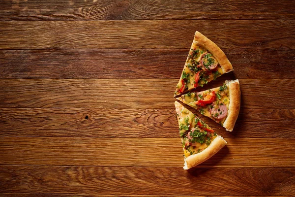 Üç dilim pizza rustik ahşap arka plan, üstten görünüm, yakın çekim, seçici odak.