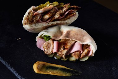 Doldurulmuş Pide ızgara sebzeler ve tavuk pirzola siyah taşlı zemin üzerine.