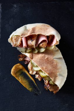 Doldurulmuş Pide ızgara sebzeler ve tavuk pirzola siyah taşlı zemin üzerine.