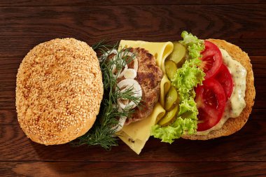 Marul, peynir, soğan ve domates ahşap arka plan üzerinde geleneksel Amerikan burger Close-up