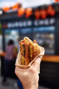 İlk kişi görünümü atış bir adam yeme hamburger sokak kafe, yumuşak odak, sığ derinlik-in tarla.