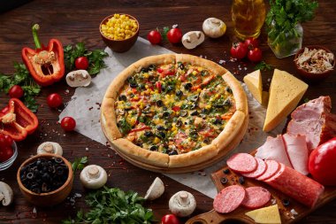 Pizza natürmort. Fırından yeni çıkmış pizza ve ahşap zemin üzerine düzenlenmiş bileşenleri.