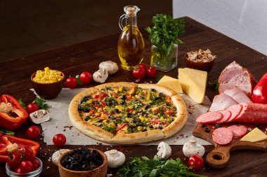 Pizza natürmort. Fırından yeni çıkmış pizza ve ahşap zemin üzerine düzenlenmiş bileşenleri.