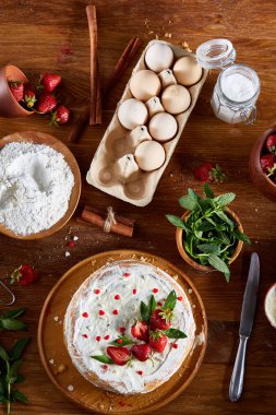 Top çilekli pasta ya da kek üzerine ahşap masa, düz yatıyordu yemek pişirmek için ham maddeler görüntüleyin. Fırın arka plan.