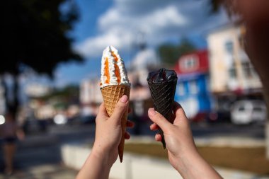 Bir dondurma sığ derinlik-in tarla onun elinde olan yol boyunca yürüyüş kadın bir ilk kişi görünümü.