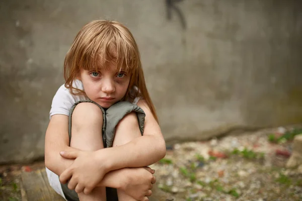 Foto de la calle de la niña huérfana con las rodillas en el callejón sucio . —  Fotos de Stock