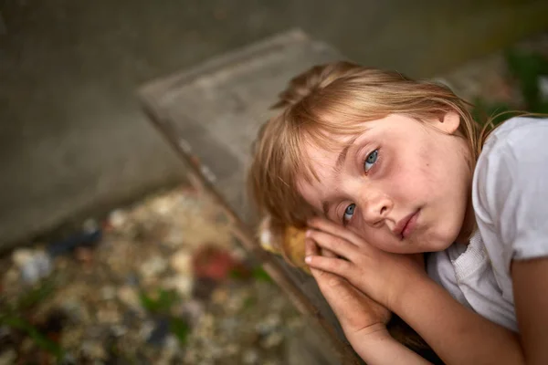 Portrait of unfortunate stray kid lying on the board in the dirty alley, shallow depth of field. — Stock Photo, Image