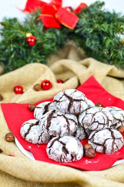 Kırmızı peçeteye beyaz kremalı zencefilli çikolata. Arka planda, bir Noel ağacının filizi.