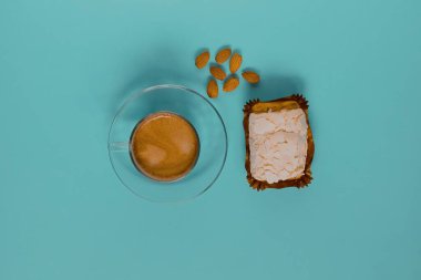 Kremalı kek ve bademli bir bardak sade kahve. Üst görünüm.