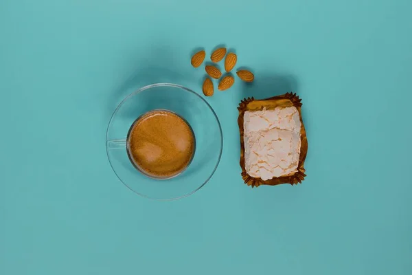 Kremalı kek ve bademli bir bardak sade kahve. Üst görünüm.