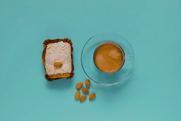 Kremalı kek ve bademli bir bardak sade kahve. Üst görünüm.