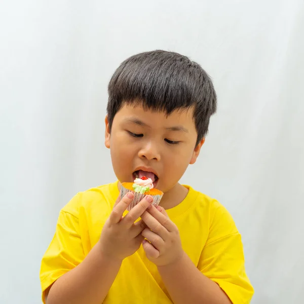 可爱的男孩吃杯蛋糕白色背景 — 图库照片