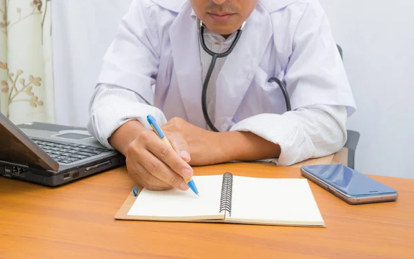 Doctor writing note book on pattern table,