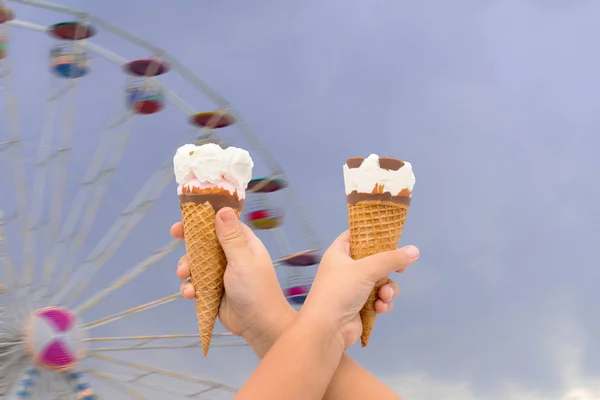 İki dondurma bulanık dönme dolap arka planda tutan el,