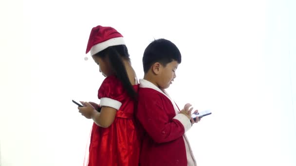 サンタの女の子と男の子の白い背景の上に一緒にスマート フォン ゲームをプレイ — ストック動画