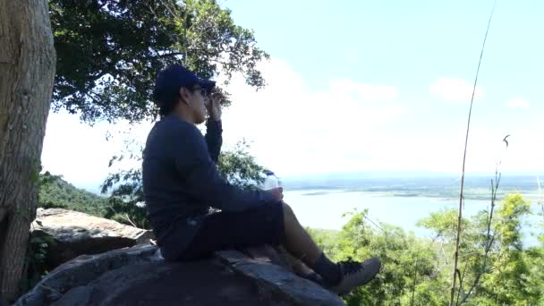 観光客の男性が湖の背景が付いている空に水を飲む — ストック動画
