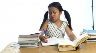 Sevimli Asya küçük kız düşünme ve beyaz arka plan üzerinde not defterine yazma,
