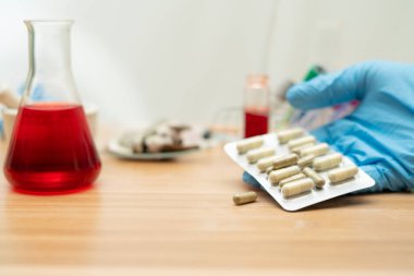 Kapsül tıbbı elinde bulanık laboratuarda bir oda arkaplanı,