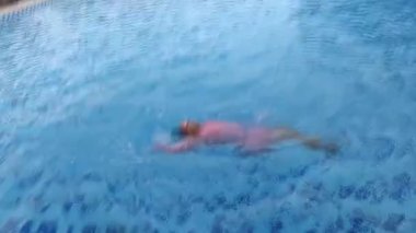 Yüzme havuzunda sürünen küçük tatlı bir kız amatör yüzücü.
