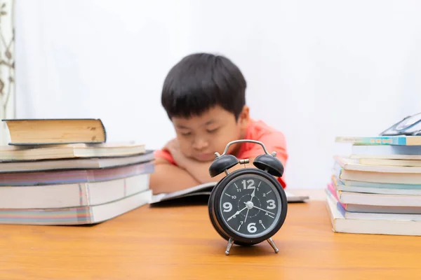 Reloj en la mesa en borrosa un niño pequeño dormir y libros espalda —  Fotos de Stock