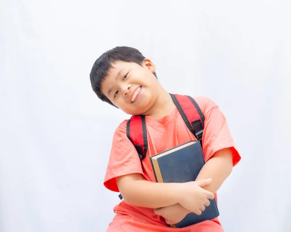En liten pojke med en bok och ett leende på vit bakgrund, — Stockfoto