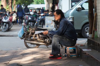 Hanoi Vietnam 20.12.2013 adam sabahın erken saatlerinde Old Quarter caddesinde oturmuş gazete okuyor. Arka planda sokak hayatı olan düşük açılı çekim yüksek kaliteli fotoğraf