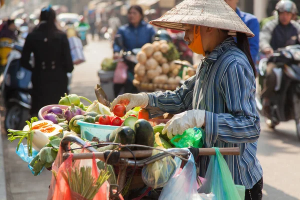 Hanoi 'deki birçok sokak satıcısı mallarını taşımak için bisiklet kullanır. Geleneksel Vietnam konik şapkalarında ağır yüklü meyve ve sebzeli bisikletlerle. Yüksek kalite fotoğraf