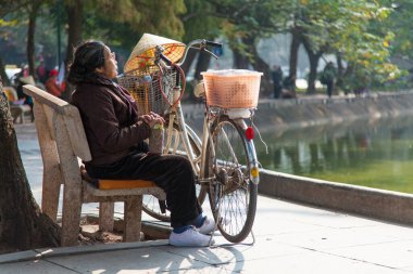 Hoan Kiem Gölü Hanoi Vietnam 20.12.2013 Hanoi Mahallesi yakınlarındaki ünlü gölün etrafında dinlenen kadın. Sabahın erken saatlerinde ziyaretçiler göl alanını egzersiz parkı olarak kullanırlar. Yüksek kalite fotoğraf