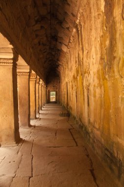 Angkor Watt, Kamboçya 'daki tapınak kompleksi, Angkor, Ta Prohm ve Bayon' un ünlü tapınakları. Tekrarlanan kemerli koridor. Eski taş işçiliğiyle sıcak altın ışık. Yüksek kalite fotoğraf.