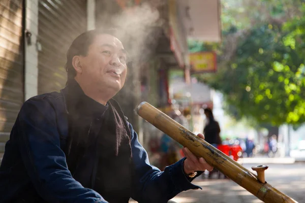 Hanoi Vietnam 20.12.2013 adamı sabahın erken saatlerinde sokakta geleneksel pipo içiyor.