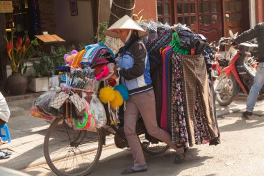 Hanoi Vietnam 20.12.2013 sokak satıcısı. Giysileri ve kumaşlarıyla bisiklet satıyor.