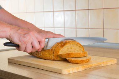 Bıçaklı eller ekmeği dilimlere böler.