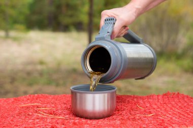 Doğada, bir el termostan yeşil çay döker.