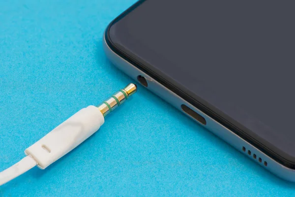 Mavi arka planda kulaklıklı bir telefon.