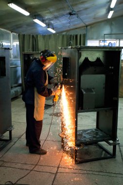 İşçi metal bir dolabı kıvılcımlarla parlatıyor