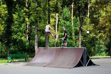 Güneşli bir günde insanların yürüdüğü parka gidiyor.