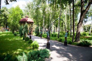 Güneşli bir günde insanların yürüdüğü uzun yeşil ağaçların olduğu parkın sokakları ve yolları.