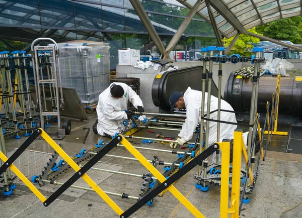 Trabalhadores reparando uma escada rolante em uma estação de trem — Fotografia de Stock