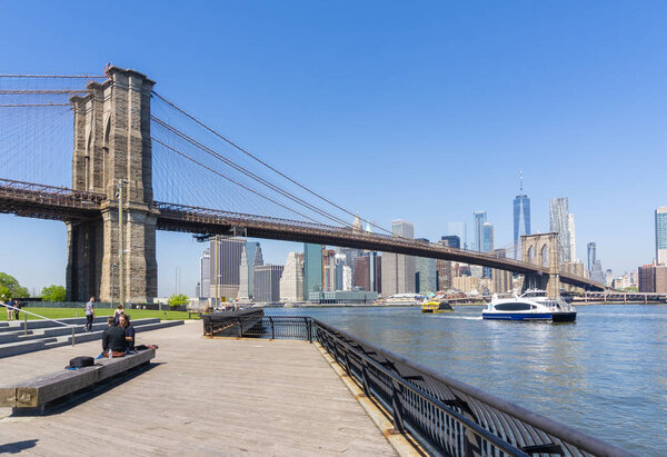 New York, USA - May 9, 2018: Tourists visiting the Brooklyn Bridge with Manhattan skyline in the background