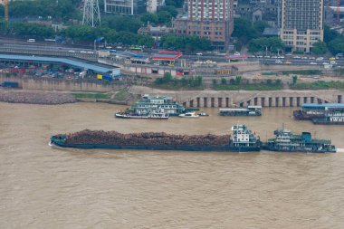 Barge full of logs crusing along a river in China clipart