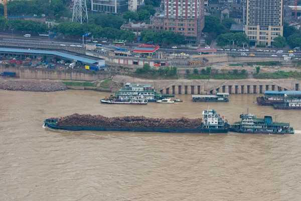 Баржа, полная бревен, крушащихся вдоль реки в Китае — стоковое фото