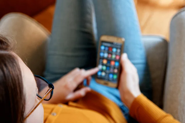 Yukardan genç bir kadının ev sarısı turuncu renkte akıllı telefon kullanması.