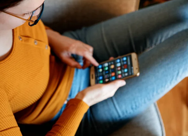 Yukardan genç bir kadının ev sarısı turuncu renkte akıllı telefon kullanması.