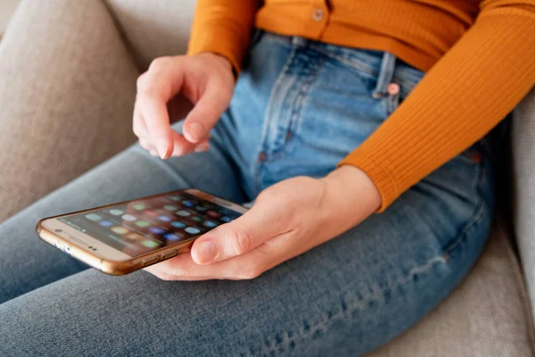 Yukardan genç bir kadının ev sarısı turuncu renkte akıllı telefon kullanması.