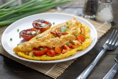 Beyaz bir tabak üzerinde Sebze yumurta omlet , kızarmış domates ile Vejetaryen omlet , taze dilimlenmiş bahar soğan ve baharat bir çuval ve eski ahşap arka plan üzerinde. Kahvaltı tarifi 