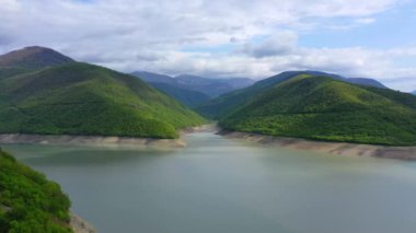 Ormanla kaplı dağlar arasında gölet. Havadan görünüm