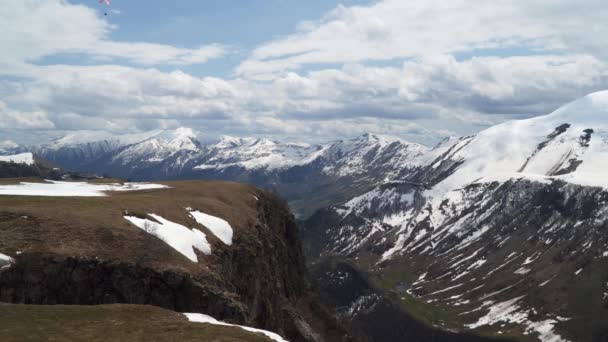 群山覆盖着雪 天空中布满了云彩 您还可以看到滑翔伞 高加索山脉 — 图库视频影像