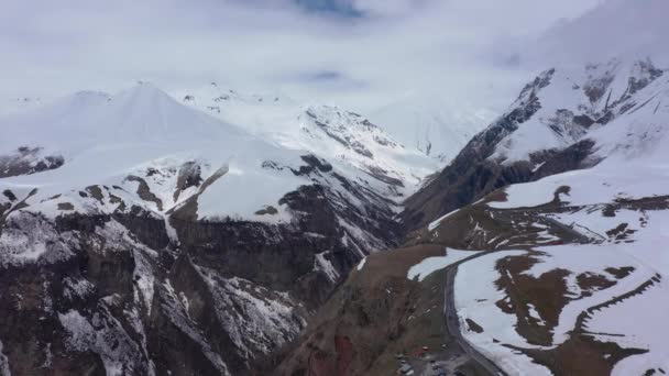 Le parapente vole parmi les montagnes enneigées. Vidéo filmée par drone 
